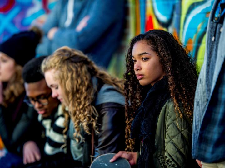 young people sitting outside in front of a graffiti wall